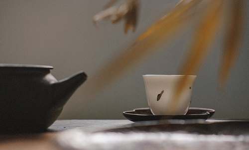 coffee cup white tea cup on black saucer near black tea pot oriental